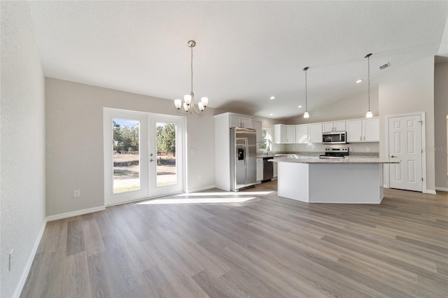 kitchen with stainless steel appliances, visible vents, hanging light fixtures, white cabinetry, and a kitchen island