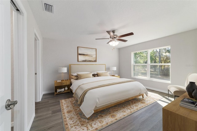 bedroom with a ceiling fan, dark wood finished floors, visible vents, and baseboards