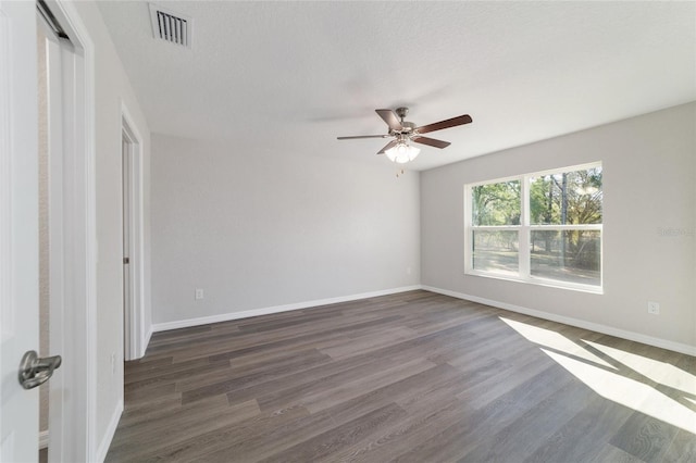 unfurnished room featuring dark wood-style flooring, visible vents, ceiling fan, and baseboards