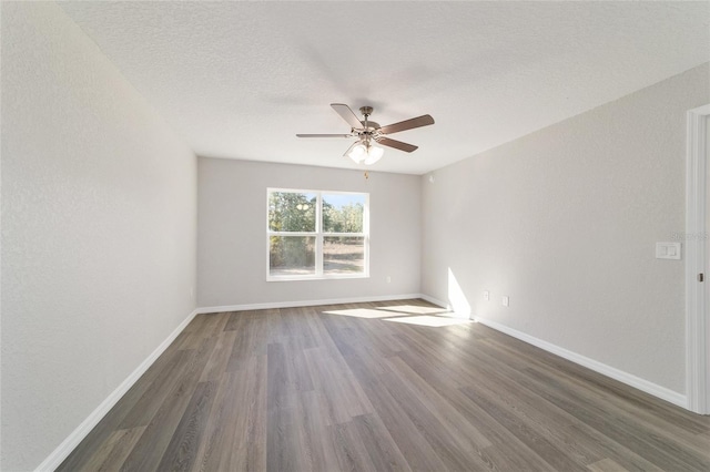 spare room featuring a textured ceiling, ceiling fan, dark wood-type flooring, and baseboards