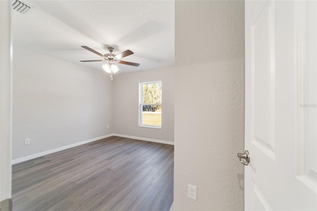 empty room with baseboards, visible vents, dark wood-style floors, ceiling fan, and a textured ceiling