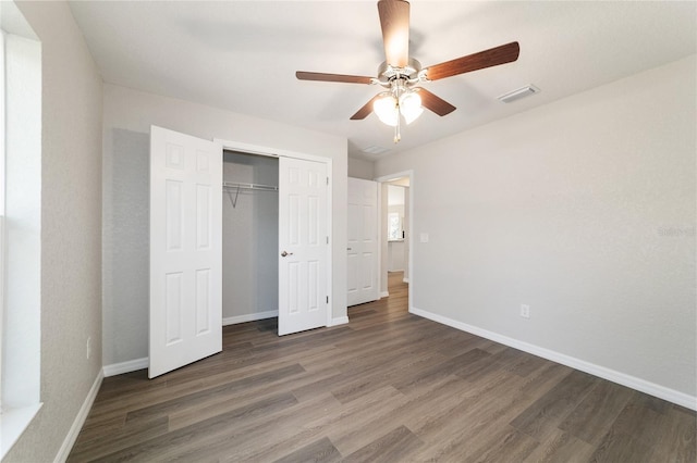 unfurnished bedroom featuring dark wood-style floors, a closet, visible vents, ceiling fan, and baseboards