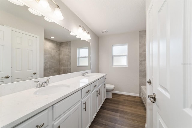 bathroom with toilet, visible vents, a sink, and wood finished floors