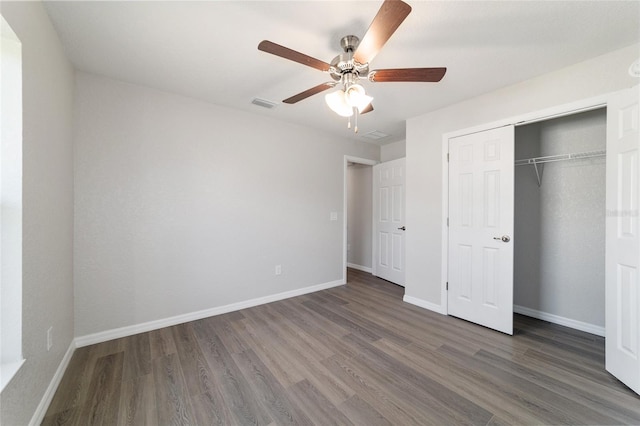 unfurnished bedroom featuring baseboards, a closet, visible vents, and dark wood-type flooring