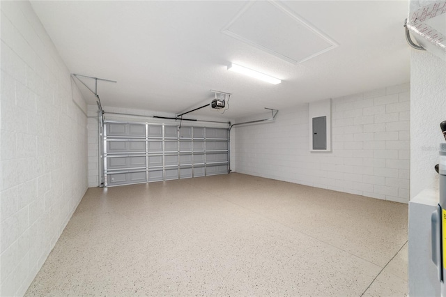 garage with concrete block wall, electric panel, and a garage door opener