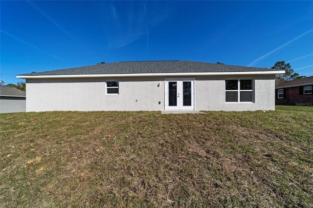 rear view of property featuring french doors, a yard, and stucco siding