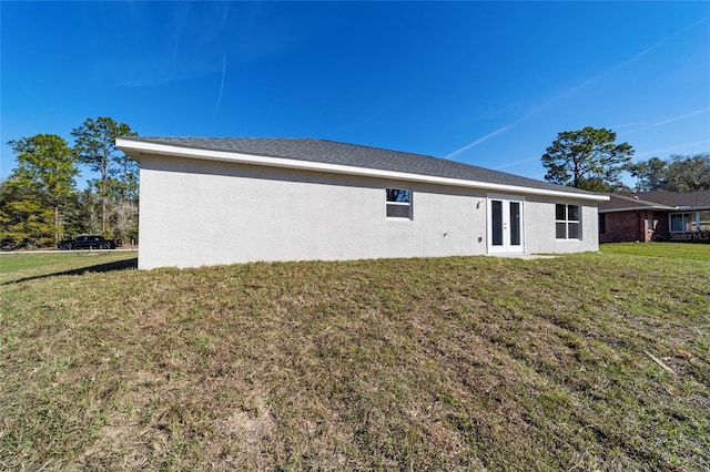 back of property featuring stucco siding and a yard