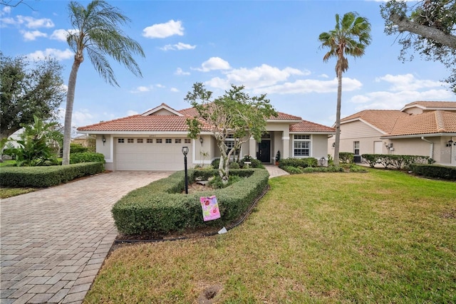 view of front of house featuring an attached garage, a tile roof, decorative driveway, and a front yard