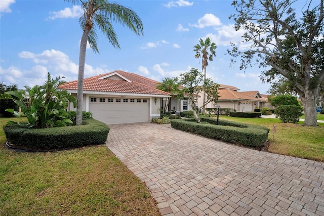 view of front of home with a garage, a tile roof, decorative driveway, a front yard, and stucco siding