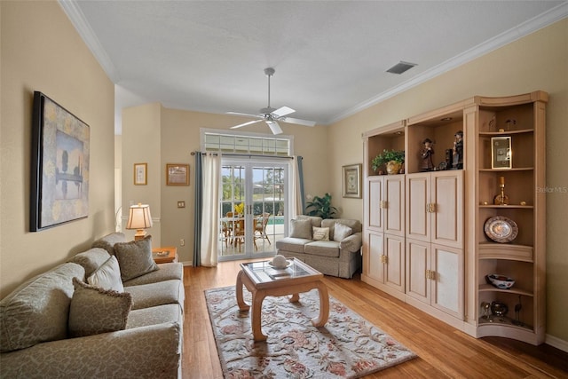 living room with ceiling fan, ornamental molding, light wood-type flooring, and visible vents