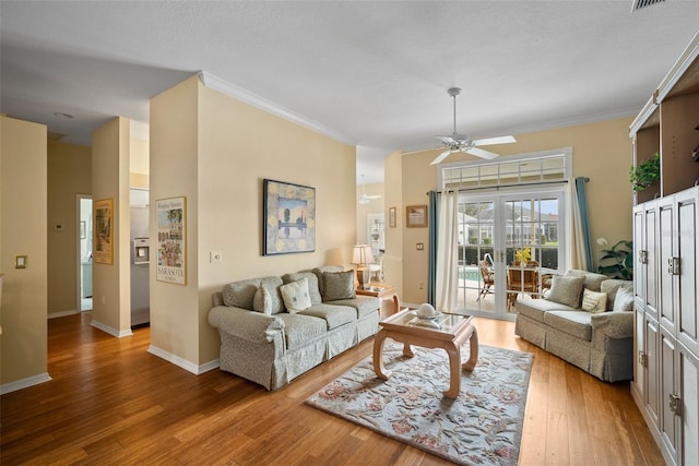 living room with ornamental molding, wood finished floors, visible vents, and baseboards