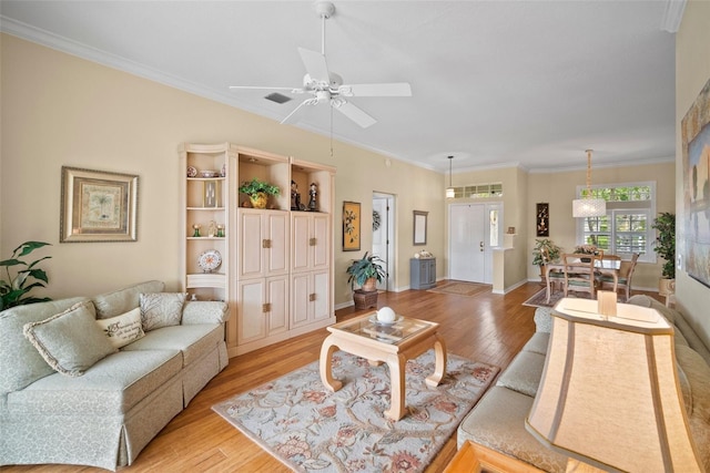 living area with light wood-style floors, crown molding, baseboards, and ceiling fan