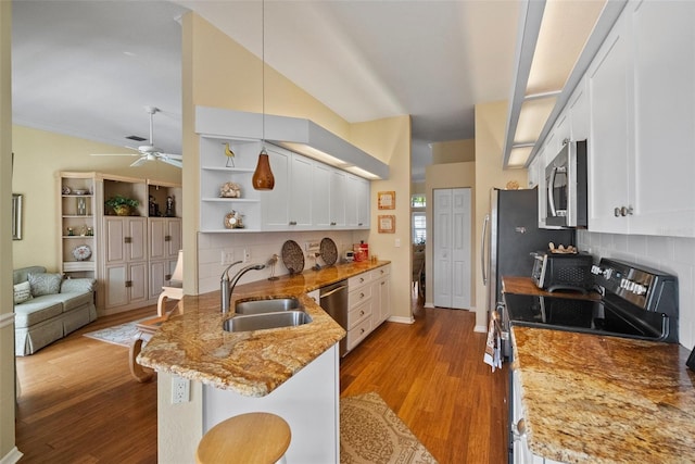 kitchen featuring a breakfast bar area, appliances with stainless steel finishes, a peninsula, white cabinetry, and a sink