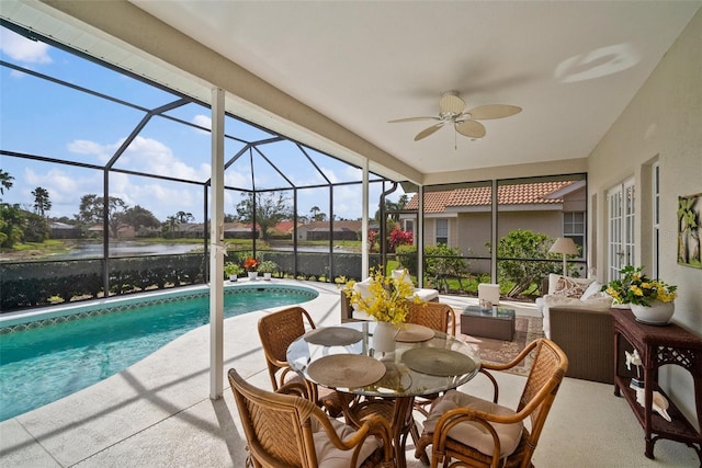 sunroom featuring a water view and a ceiling fan