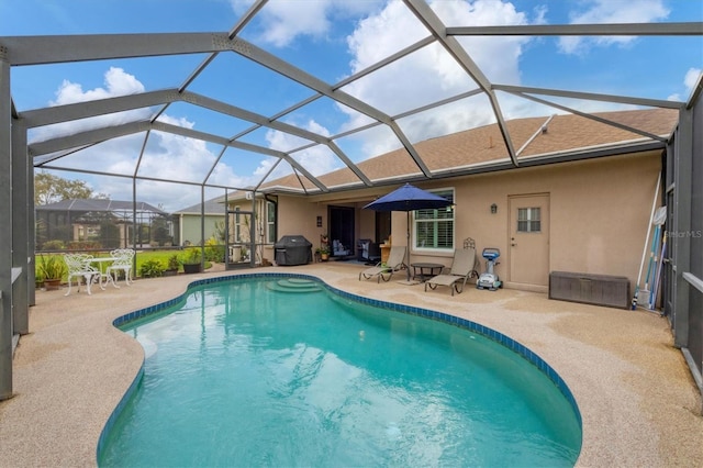 outdoor pool featuring a patio area, glass enclosure, and grilling area