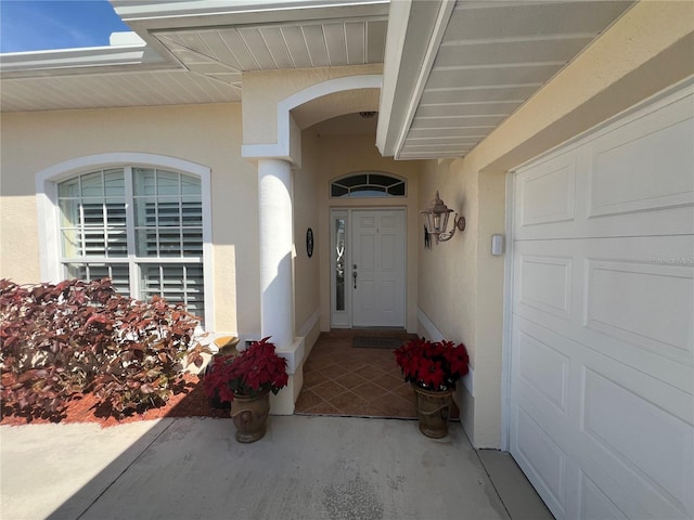 view of exterior entry featuring a garage and stucco siding