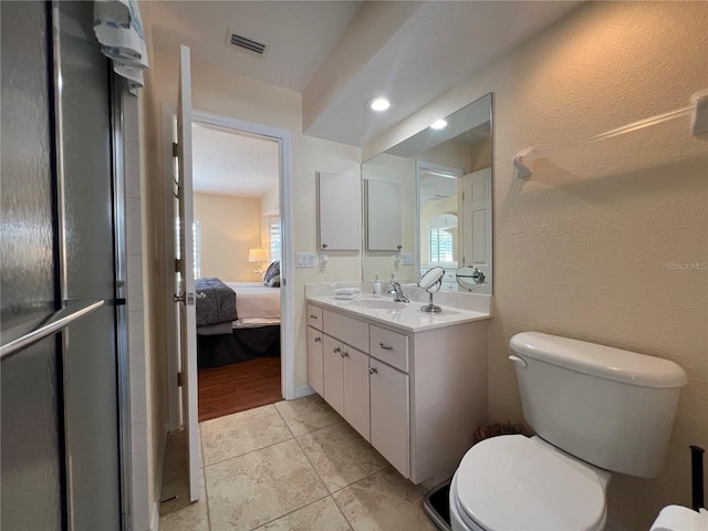 ensuite bathroom with a textured wall, toilet, vanity, visible vents, and ensuite bath