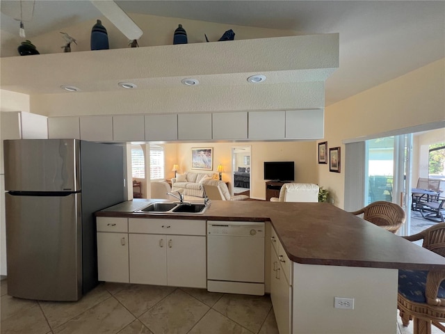 kitchen with a sink, dark countertops, dishwasher, and freestanding refrigerator