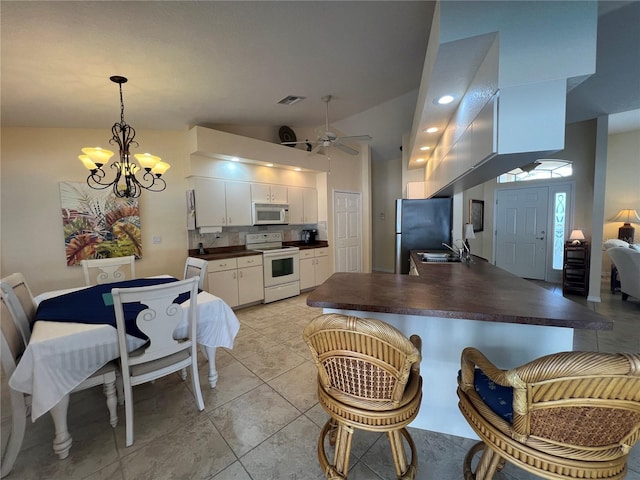 kitchen with white appliances, visible vents, dark countertops, a peninsula, and a sink