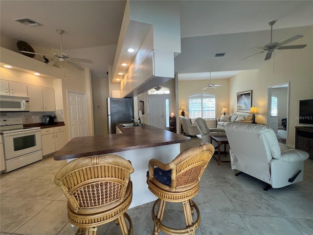 kitchen with dark countertops, visible vents, open floor plan, white cabinets, and white appliances