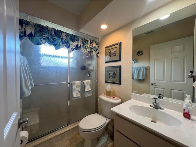 full bath featuring a stall shower, a textured wall, vanity, and toilet