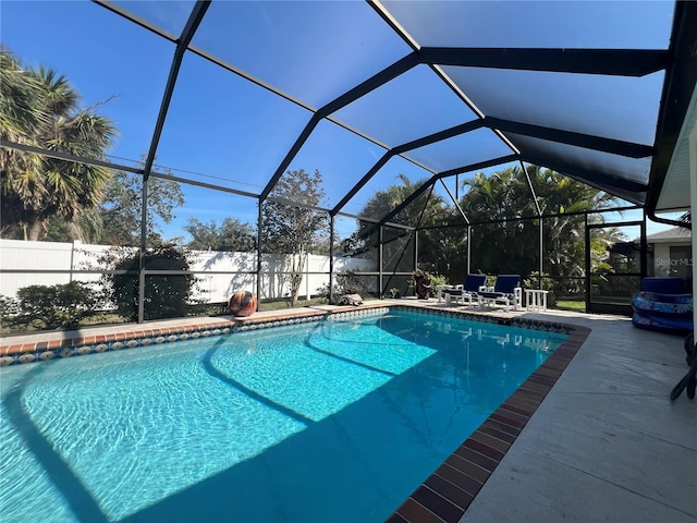 view of pool featuring glass enclosure, fence, a fenced in pool, and a patio