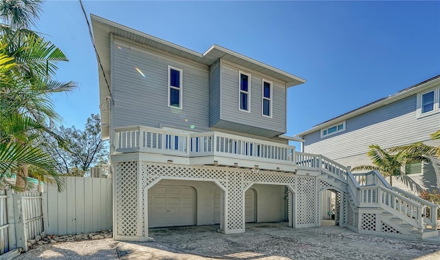 rear view of house featuring stairs, an attached garage, fence, and a wooden deck