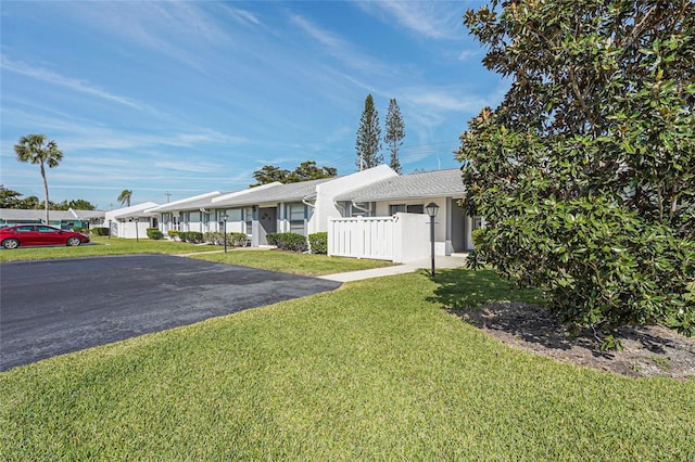 ranch-style home featuring a front yard, fence, and stucco siding