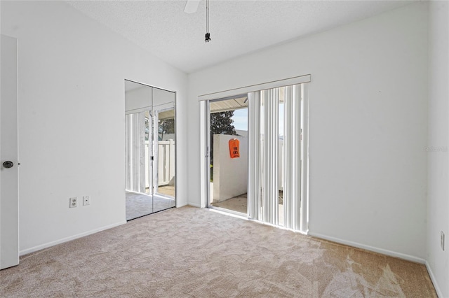 unfurnished bedroom with a textured ceiling, light carpet, a ceiling fan, vaulted ceiling, and access to outside