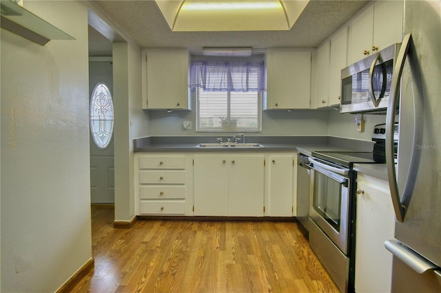 3658 Lake Bayshore Dr Unit 320, Bradenton, FL 34205 - kitchen with light wood-type flooring, appliances with stainless steel finishes, white cabinets, and a sink