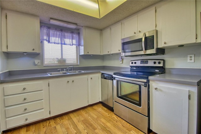 3658 Lake Bayshore Dr Unit 320, Bradenton, FL 34205 - kitchen with a textured ceiling, stainless steel appliances, a sink, white cabinets, and light wood finished floors