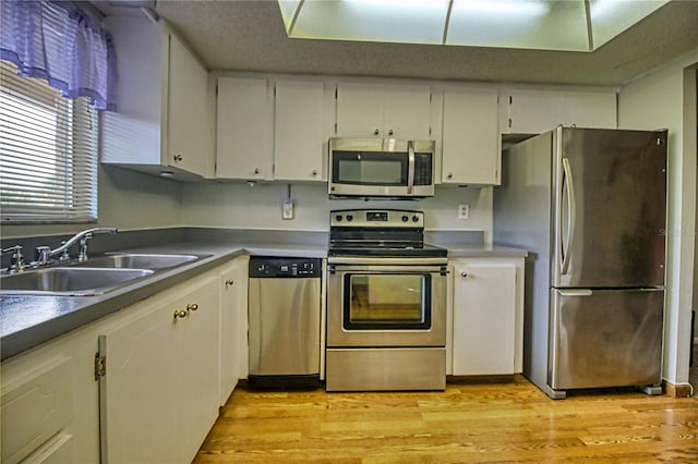 3658 Lake Bayshore Dr Unit 320, Bradenton, FL 34205 - kitchen with appliances with stainless steel finishes, white cabinetry, a sink, and light wood-style flooring