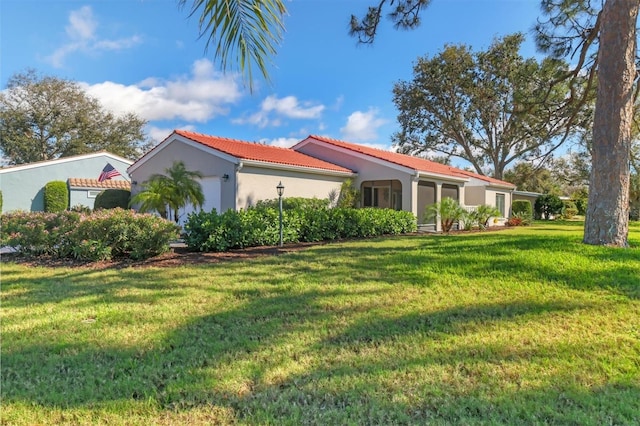 exterior space with a garage, a tiled roof, a front lawn, and stucco siding