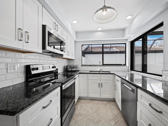 kitchen featuring tasteful backsplash, white cabinets, appliances with stainless steel finishes, a sink, and light tile patterned flooring