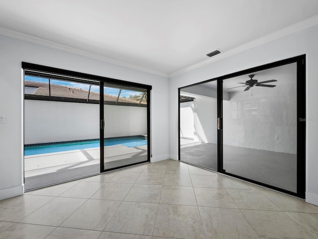 empty room featuring light tile patterned floors, baseboards, visible vents, a ceiling fan, and ornamental molding