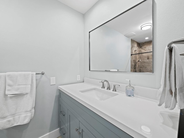 full bathroom featuring tiled shower, vanity, and baseboards