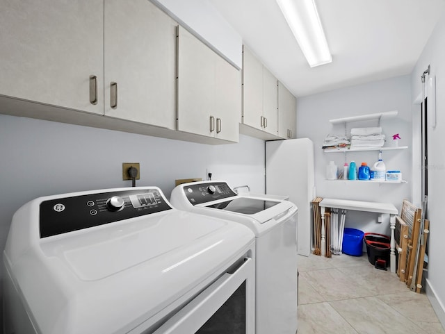 laundry room featuring light tile patterned floors, separate washer and dryer, and cabinet space