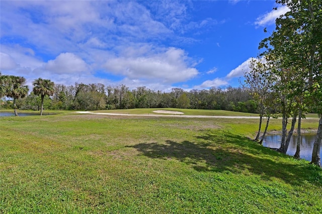 exterior space featuring a water view, a wooded view, and a yard