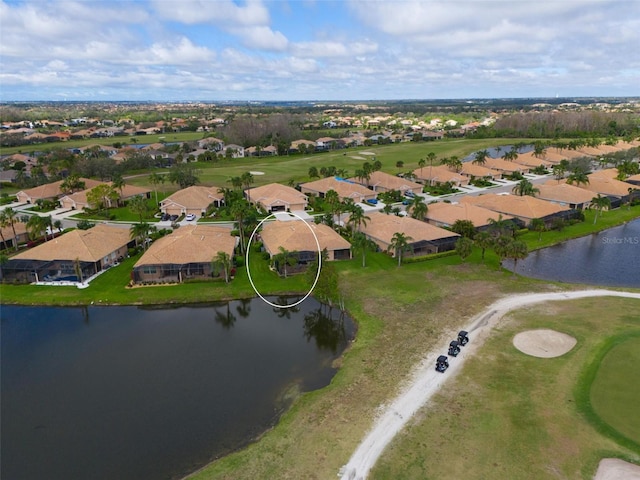 drone / aerial view with golf course view, a water view, and a residential view