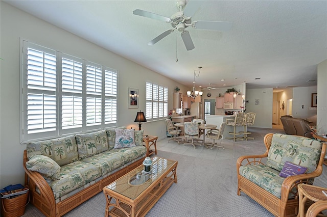 living area with light carpet, a textured ceiling, and ceiling fan with notable chandelier