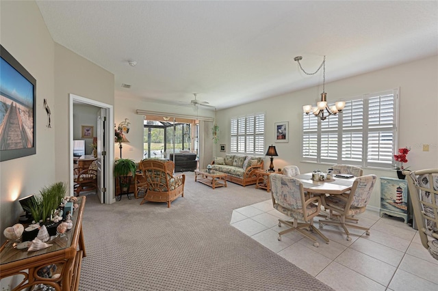 dining area with light carpet, light tile patterned floors, and ceiling fan with notable chandelier