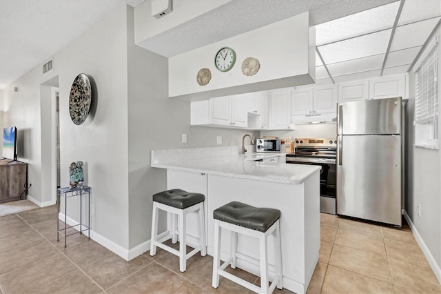 kitchen with stainless steel appliances, light countertops, visible vents, a peninsula, and under cabinet range hood