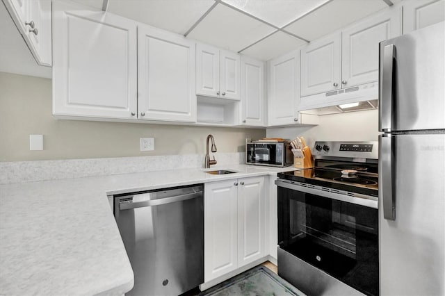 kitchen featuring under cabinet range hood, a sink, white cabinets, light countertops, and appliances with stainless steel finishes