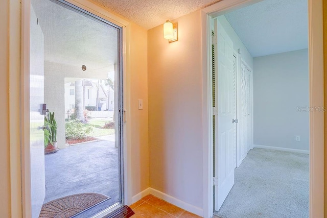 entryway featuring a textured ceiling, tile patterned flooring, and baseboards