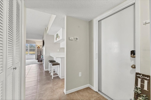 interior space featuring a textured ceiling, baseboards, and light tile patterned floors