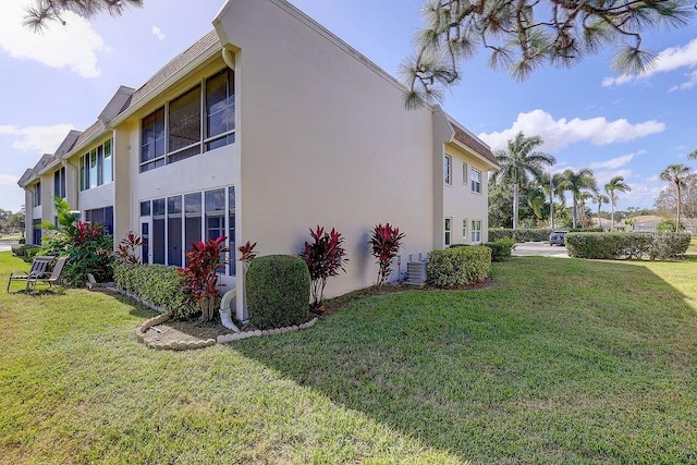 view of property exterior with a yard, central AC unit, and stucco siding