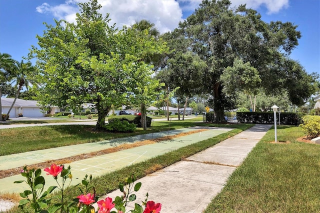 view of property's community with a lawn and shuffleboard