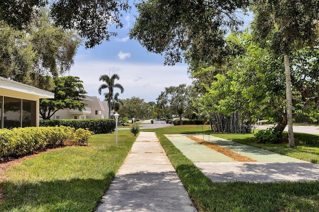 view of property's community featuring shuffleboard and a lawn