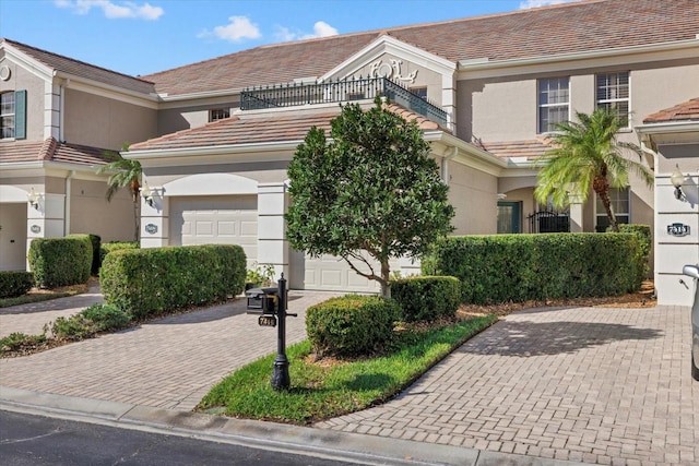 townhome / multi-family property featuring a garage, a tiled roof, decorative driveway, and stucco siding