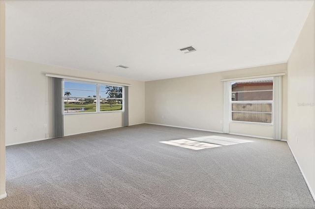 spare room featuring carpet flooring, visible vents, and baseboards